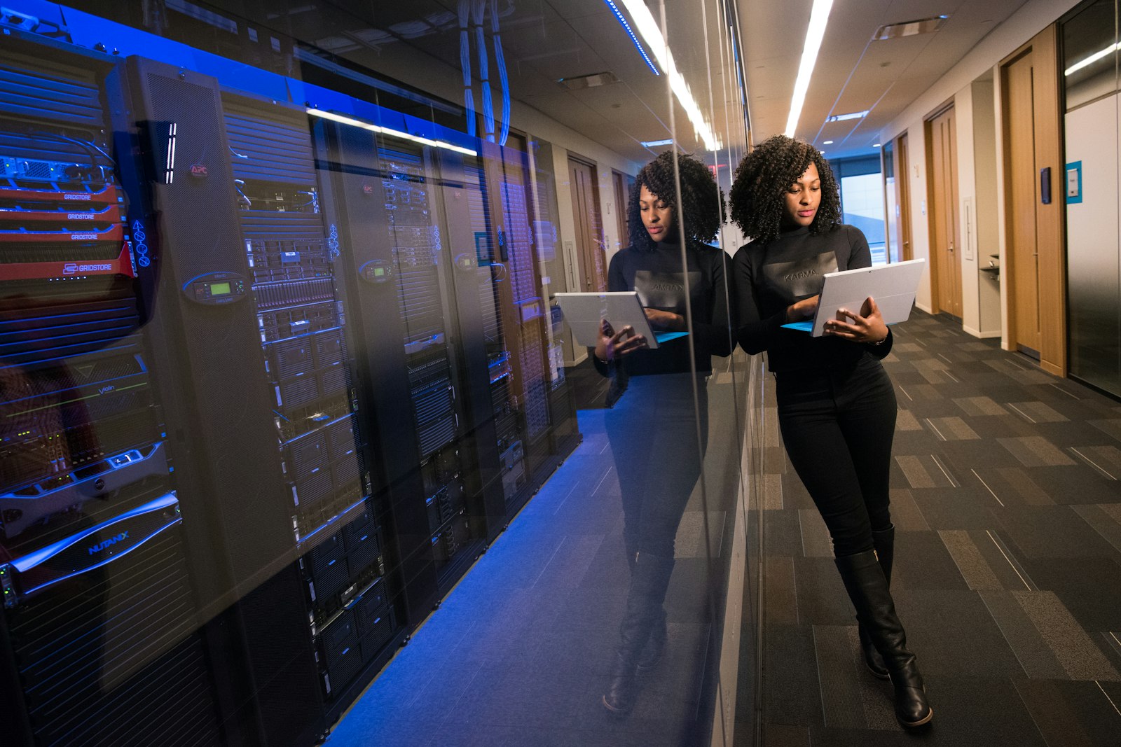 Professional walking through a glass-walled office corridor